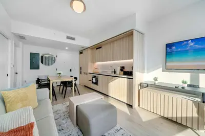 a living room with a couch and a kitchen with a tv at Downtown Edit-Resort Style Stay with Full Amenities in Miami