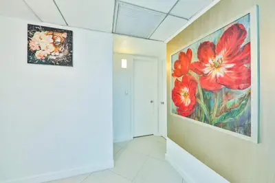 a painting of red flowers on a wall in a hallway at Family getaway steps from the ocean STR-01305 in Sunny Isles Beach