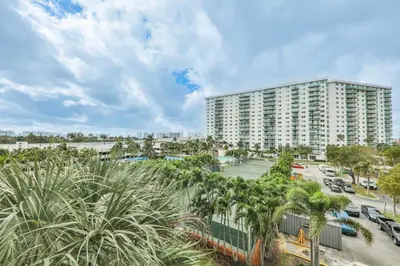 an apartment building with palm trees and a parking lot at Family getaway steps from the ocean STR-01305 in Sunny Isles Beach