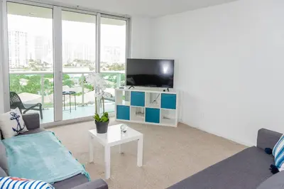 a living room with a tv and a couch and a table at Condo on the Beach-STR 01309 in Sunny Isles Beach