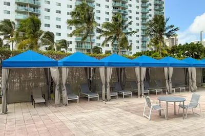 a patio with blue umbrellas and chairs and tables at Condo on the Beach-STR 01309 in Sunny Isles Beach