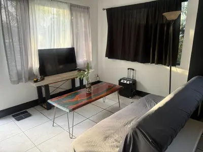a living room with a tv and a table and a bed at paradise in North Miami Beach