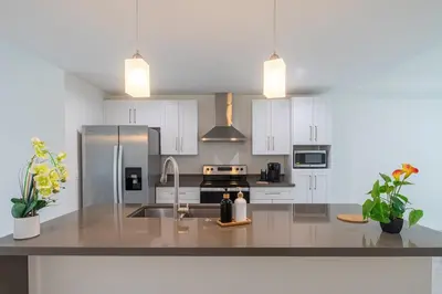 a kitchen with white cabinets and a stainless steel refrigerator at 3BR Getaway, 4 Beds, Near Beach, Free Parking in Hallandale Beach