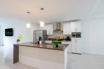 a kitchen with white cabinets and a large counter top at 3BR Getaway, 4 Beds, Near Beach, Free Parking in Hallandale Beach