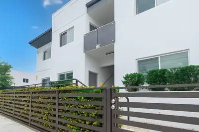 a fence in front of a white building at Modern 3BR Getaway 4 Beds with Free Parking Included in Hallandale Beach
