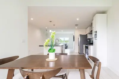 a kitchen and dining room with a wooden table and chairs at Stylish 3BR Apartment, 4 Beds, Great for Groups with Free Parking in Hallandale Beach