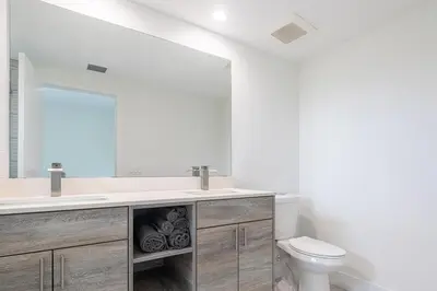 a bathroom with a sink and a toilet and a mirror at Stylish 3BR Apartment, 4 Beds, Great for Groups with Free Parking in Hallandale Beach