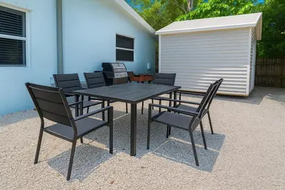 a black table and chairs and a building at Comfy 2BR Apartment Near Las Olas with Patio, BBQ and FREE PARKING in Fort Lauderdale