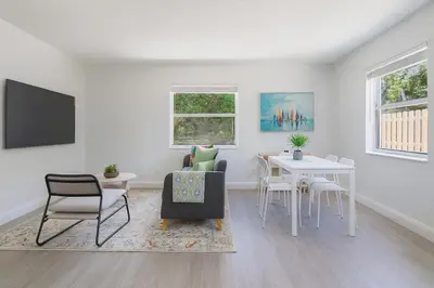 a living room with a table and a chair at Comfy 2BR Apartment Near Las Olas with Patio, BBQ and FREE PARKING in Fort Lauderdale