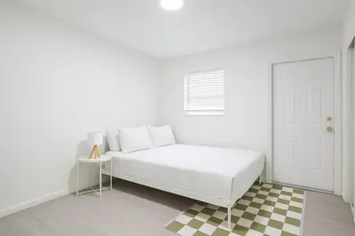a white bedroom with a bed and a window at Comfy 2BR Apartment Near Las Olas with Patio, BBQ and FREE PARKING in Fort Lauderdale