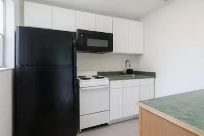 a kitchen with a black refrigerator and white cabinets at Comfy 2BR Apartment Near Las Olas with Patio, BBQ and FREE PARKING in Fort Lauderdale