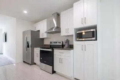 a kitchen with white cabinets and stainless steel appliances at Comfortable 3BR Apartment, 4 Beds, Free Parking Included in Hallandale Beach