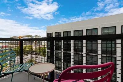 a balcony with chairs and a table and a building at Voy House Wynwood with Rooftop Pool in Miami