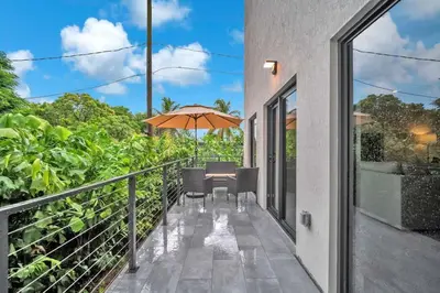 a balcony with a table and an umbrella at Sandra's Place - Family - Entire 8BR-6BA in Miami