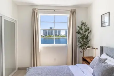 a bedroom with a bed and a large window at Serene Waterfront Condo - Bayview, pool & tennis in Aventura