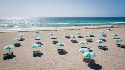 a bunch of umbrellas on a beach with the ocean at Casa Collins in Miami Beach