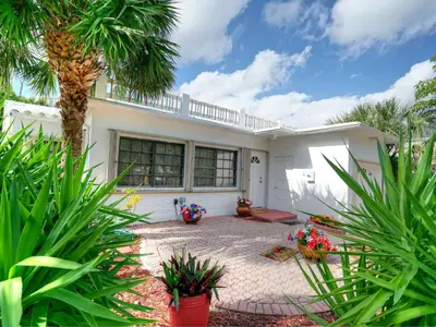 a white house with a palm tree and plants at Holiday Home Guest House at the Ocean by Interhome in Fort Lauderdale
