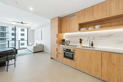 a kitchen with wooden cabinets and a table in a room at Miami Highline- Sauna Heated Pool Cabanas in Miami