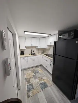 a kitchen with white cabinets and a black refrigerator at PrimeStay Modern Studio in Prime Location in Hollywood