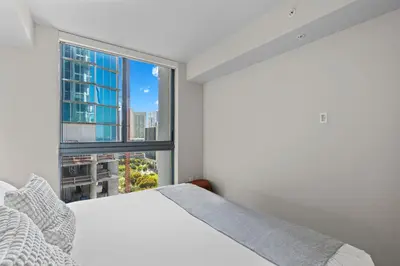 a bedroom with a white bed and a large window at Downtown Stay with Rooftop Pool Amenities in Miami