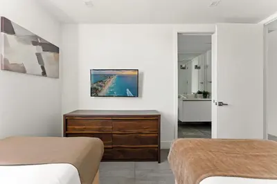 a bedroom with two beds and a dresser and a bathroom at South Beach 2Q Moderno a 5 min da Praia in Miami Beach