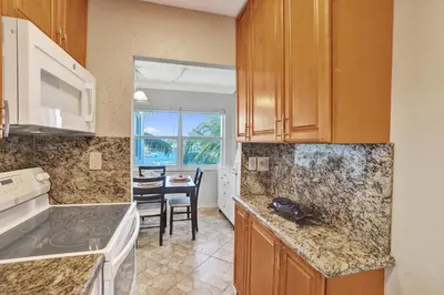 a kitchen with wooden cabinets and a dining room at Fort Lauderdale Waterfront Condo! Pool and Marina Views in Fort Lauderdale