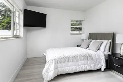 a white bedroom with a bed and a flat screen tv at Harbor Beach in Fort Lauderdale