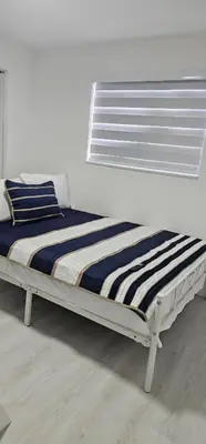 a bed in a white room with a window at Sunrise Oasis in Sunrise