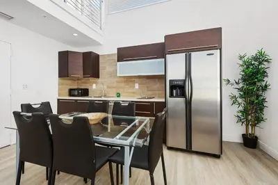 a kitchen with a table and a stainless steel refrigerator at Art Deco Ocean Drive Suites in Miami Beach