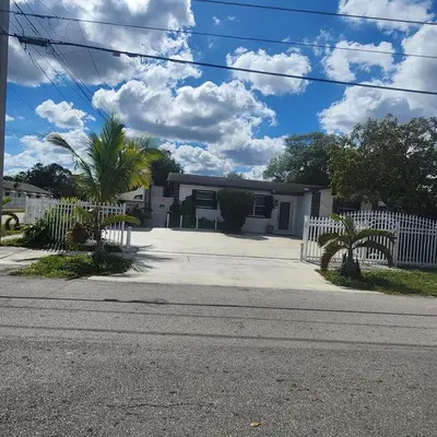 a house with a white fence and palm trees at Amazing room in Hollywood in Carver Ranches