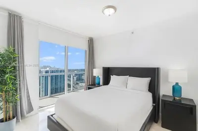 a bedroom with a white bed and a large window at Icon Brickell Penthouse Panoramic Skyline by IliosRentals in Miami