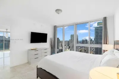 a white bedroom with a bed and a tv at Icon Brickell Penthouse Panoramic Skyline by IliosRentals in Miami