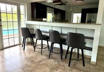 a kitchen with a bar with black chairs around it at House across from Baptist Hospital in Sunset Corners