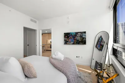 a bedroom with a white bed and a mirror at Modern Downtown Miami Condo w Pool and Gym in Miami