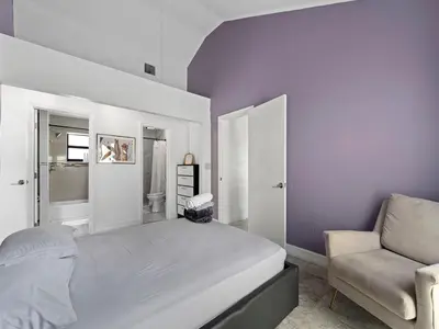 a bedroom with a large bed and a chair at The Gilded Palm - Near Design District - Pool & Hot Tub in Miami