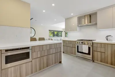 a kitchen with wooden cabinets and a stove top oven at Hollywood Palms: Mins to beach, Pool, Spa, BBQ in Hollywood