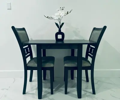 a black table with two chairs and a vase with flowers at The Luxe Studio in Miami Gardens