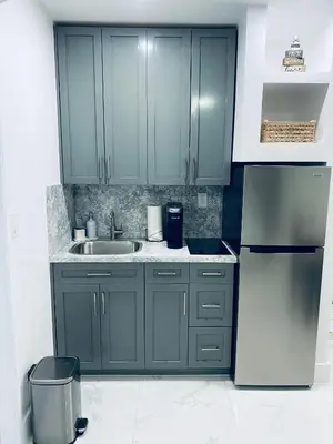 a kitchen with green cabinets and a sink and a refrigerator at The Luxe Studio in Miami Gardens
