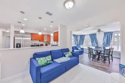 a living room with a blue couch and a kitchen at Chill Zona Arizona Villa Perfect Cruise Stay in Fort Lauderdale