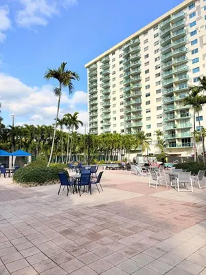 a patio with chairs and tables in front of a large building at Modern 2BR beachfront with pool & tennis view in Sunny Isles Beach