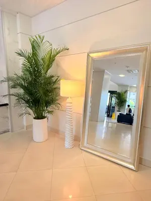 a mirror and a lamp and a plant in a room at Modern 2BR beachfront with pool & tennis view in Sunny Isles Beach