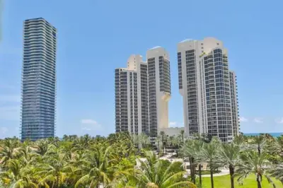a group of tall buildings with palm trees in front at Center of Joy in Sunny Isles Beach