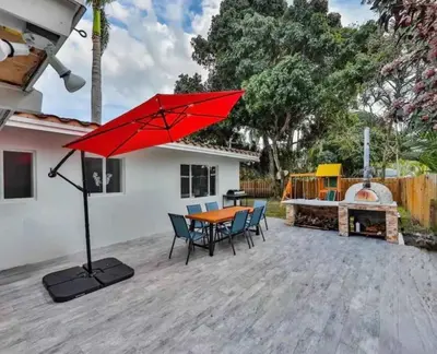 a red umbrella on a patio with a table and chairs at Quiet family vacation minutes from Airport in Fort Lauderdale