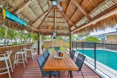 a wooden table and chairs on a deck with a pool at LUX View Villa in Fort Lauderdale