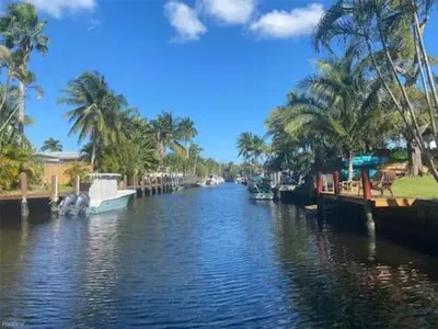 a river with boats docked next to palm trees at LUX View Villa in Fort Lauderdale