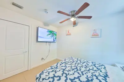 a bedroom with a ceiling fan and a tv at Student Villa House STR-2000 in Hollywood
