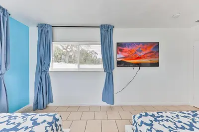a bedroom with blue curtains and a tv on the wall at Lucky Family Charm STR-2750 in Hollywood