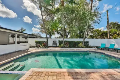a swimming pool with blue chairs in a backyard at Hollywood Family Vibes in Hollywood