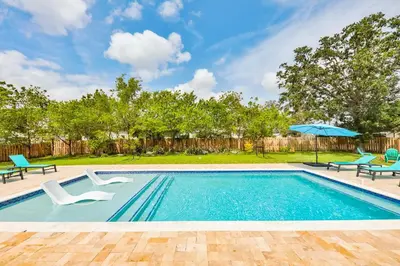 a swimming pool with two chairs and an umbrella at A star is born villa in Hallandale Beach