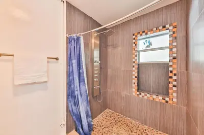 a bathroom with a shower with a blue shower curtain at Release your nature in Hallandale Beach